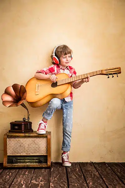 Kid listen music home hipster child with retro vintage acoustic guitar