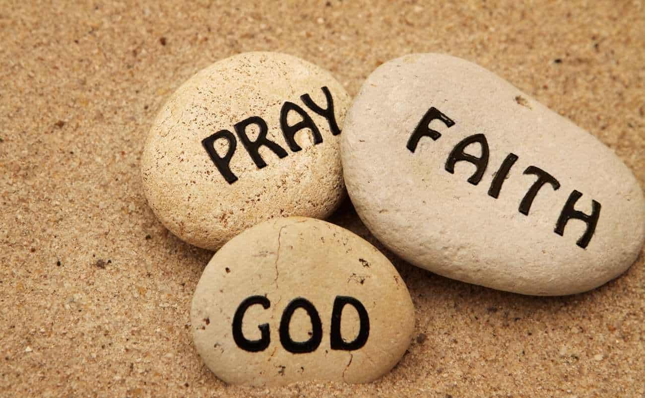 Pray, faith, and God words written on stones on sandy background, inspirational Christian message for prayer, faith, worship, and spirituality concepts for biblical songs and religious devotion.