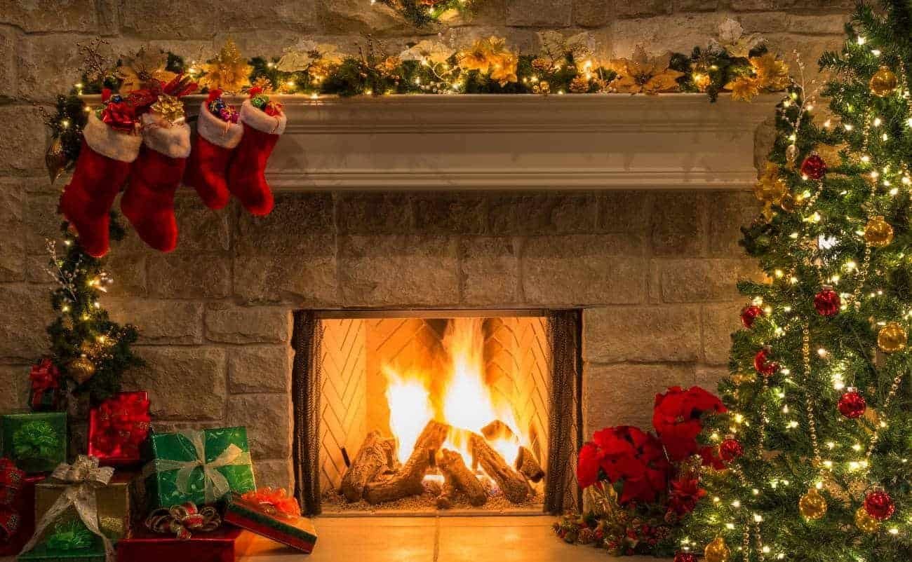 Christmas fireplace decorated with stockings and gifts, holiday lights, and Christmas tree, creating a warm, festive scene for celebrating the Christmas season and sharing the joy of Jesus' birth.