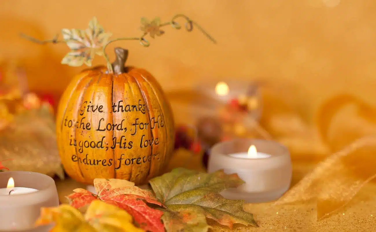 Pumpkin with inspirational Bible verse, surrounded by autumn leaves and candles, perfect for fall religious or gratitude-themed content.