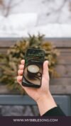 Delicious coffee with inspirational Bible verse on smartphone screen, promoting faith-based music and Christian apps, ideal for religious content, prayer, worship, and spiritual encouragement.