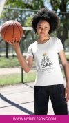 Young girl holding a basketball outdoors, wearing a T-shirt with a biblical verse about God's plan and guidance for life.