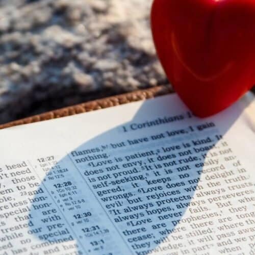 Joyful bible open with reading scripture and a red heart, symbolizing love and faith in God, ideal for Christian worship, biblical study, and spiritual growth.