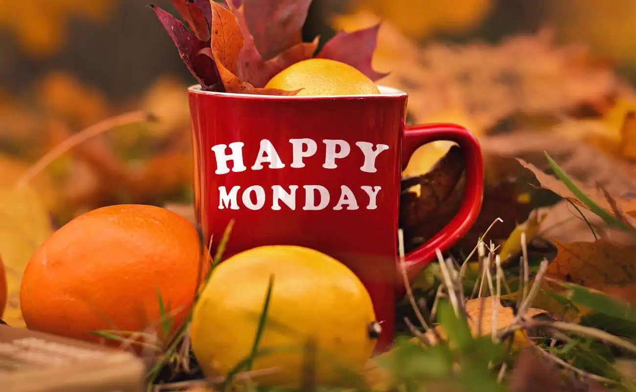 Red mug with "HAPPY MONDAY" text surrounded by autumn leaves and apples, symbolizing a cheerful start to the week for Bible verse inspiration and faith-based motivation on Mondays.