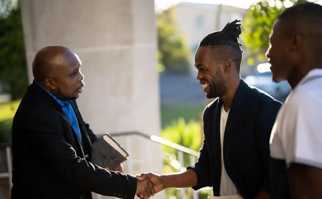 Friendly handshake between diverse men outside, symbolizing faith, community, and spiritual connection with a focus on Christian values and Bible-based worship.