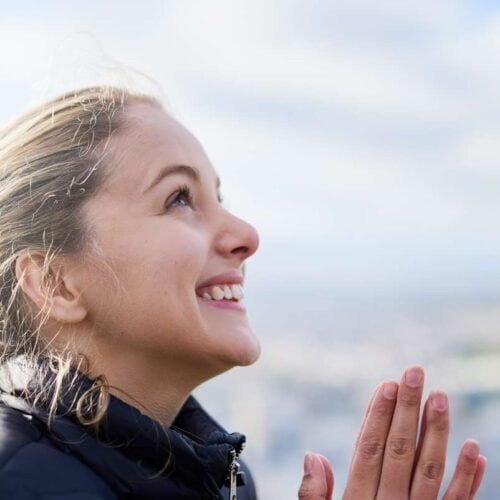Praying woman outdoors with hands clasped, symbolic of faith and devotion, representing the spiritual connection to God and the essence of Christian prayer.
