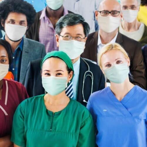 Essential healthcare professionals wearing masks, diverse medical team, frontline workers, hospital staff, medical team leadership, healthcare workers in protective gear, team of doctors and nurses, clinical staff in medical scrubs, pandemic response team, medical professionals at work.