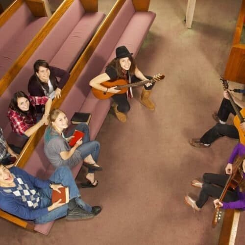 A group of young people singing and playing guitars in a church choir, sharing Christian music and biblical songs for worship.