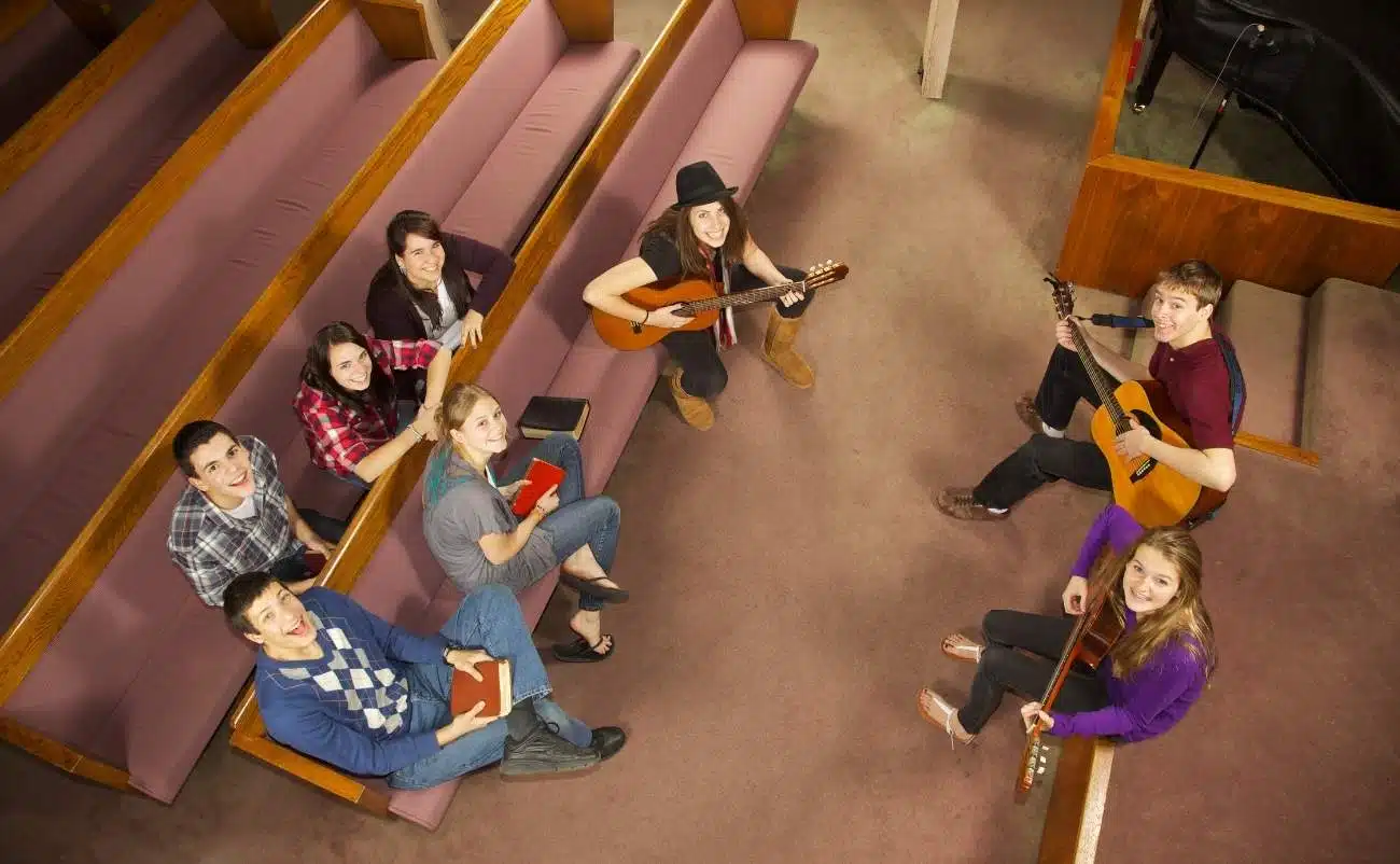 A group of young people singing and playing guitars in a church choir, sharing Christian music and biblical songs for worship.