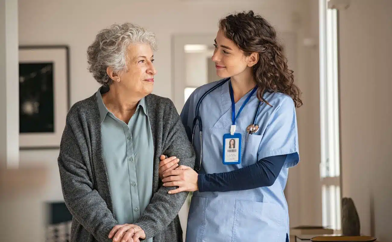 Compassionate nurse supporting elderly female patient in healthcare setting, emphasizing kindness and caregiving, with My Bible Song branding for faith-based inspiration.
