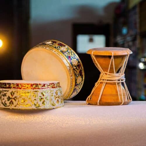 Colorful traditional percussion instruments including tambourine and drum on a white cloth, used in Christian worship and religious music, emphasizing faith and praise through song.