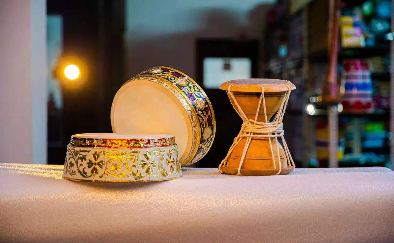 Colorful traditional percussion instruments including tambourine and drum on a white cloth, used in Christian worship and religious music, emphasizing faith and praise through song.