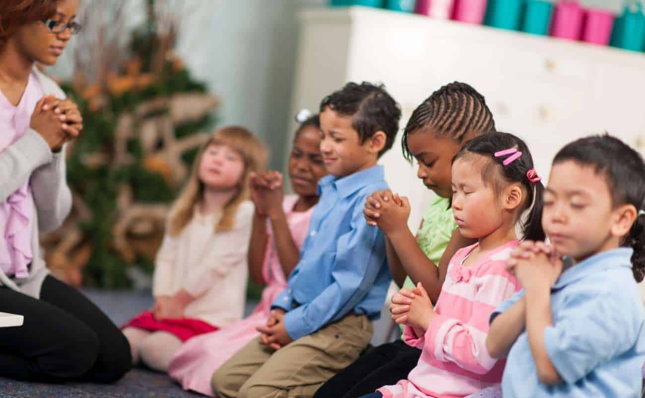 Powerful Trinity Sunday Prayers to Enrich Your Faith My Bible Song 2025 Kids praying during a Bible lesson, children praying in church or Sunday school, focusing on faith and spirituality, group prayer for kids, Christian education for children.