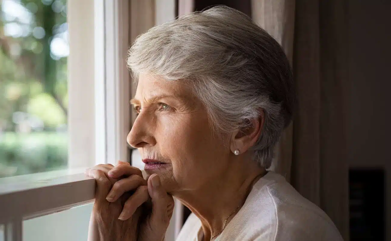 Elderly woman looking out a window with hope and peace, contemplating faith and prayer, symbolizing spiritual reflection and trust in God for inspiration and guidance in daily life, representing religious devotion and inner peace.