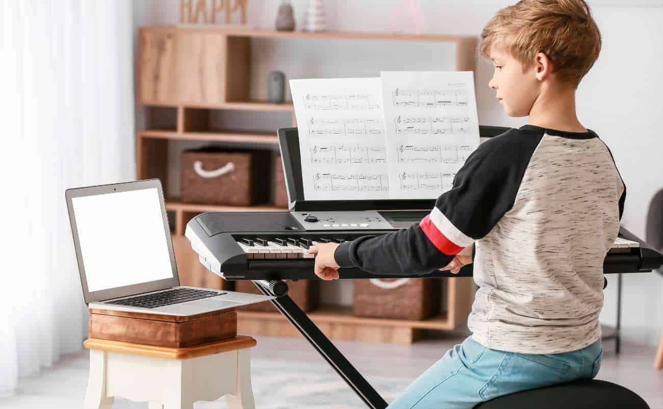 Playing kid on digital keyboard with sheet music, music practice, worship, and faith music for children, learning to sing praises and worship songs for kids on electronic keyboard, music education for young musicians.