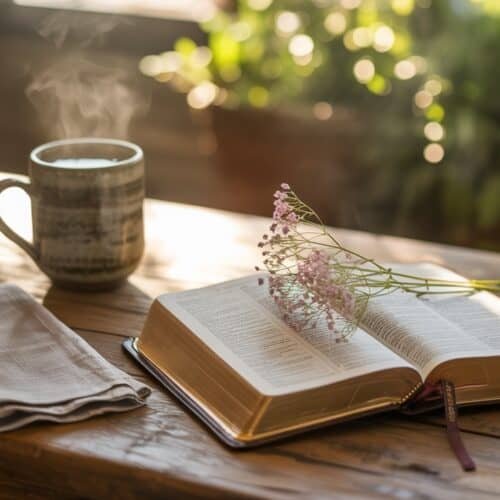 Father’s Day Quotes from the Bible to Honor Dad My Bible Song 2026 Bible open with pink flowers and steam rising in a peaceful, natural setting, featuring a coffee mug, napkin, and sunlight filtering through greenery. Ideal for inspiring faith and spiritual reflection.