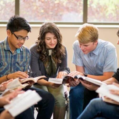 16 Uplifting Scripture for Friendship That Celebrate the Beauty of Friendship My Bible Song 2025 A diverse group of teenagers gathered in a classroom, reading the Bible together with focus and engagement, promoting faith, youth spirituality, and Christian community.