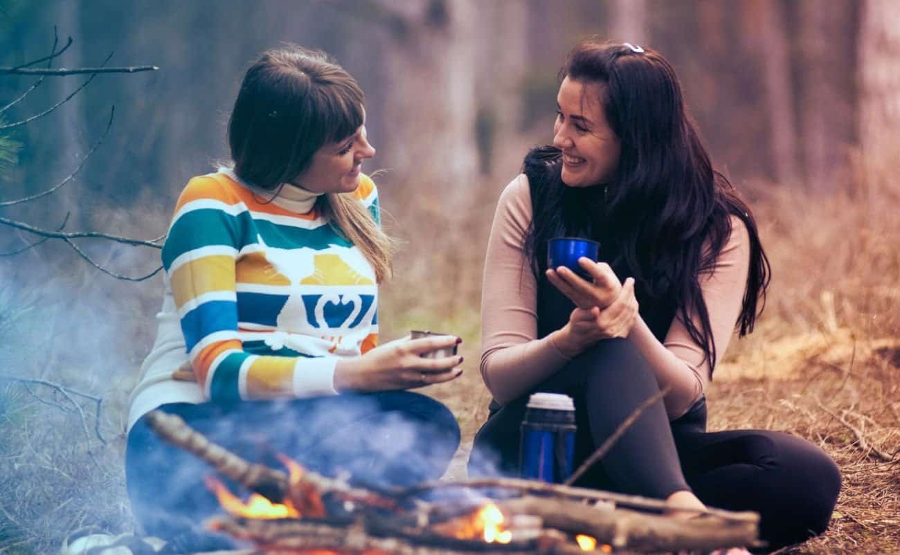 Joyful women sharing faith and friendship outdoors, enjoying a Bible-themed song and spiritual connection in a peaceful forest setting.