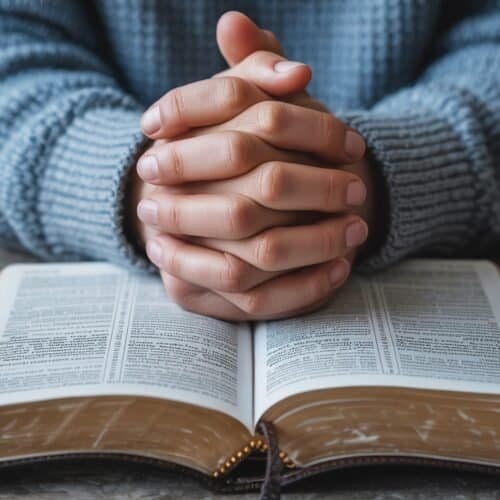 Prayer hands over open Bible with reflections of faith and devotion, emphasizing worship and spiritual connection.