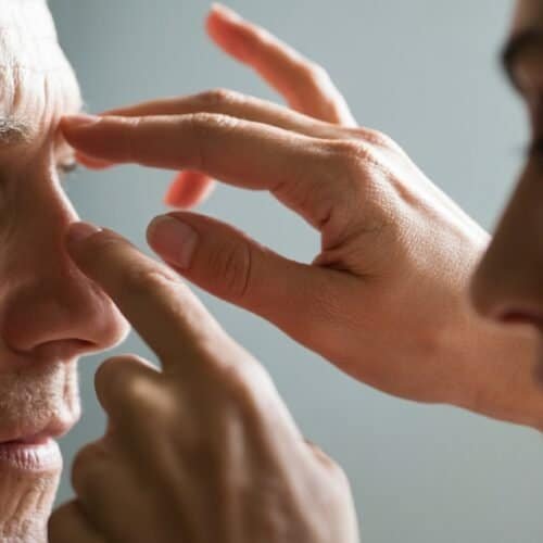 A person gently placing their fingers on another person's forehead, symbolizing prayer or blessing, with a focus on spiritual connection and faith.