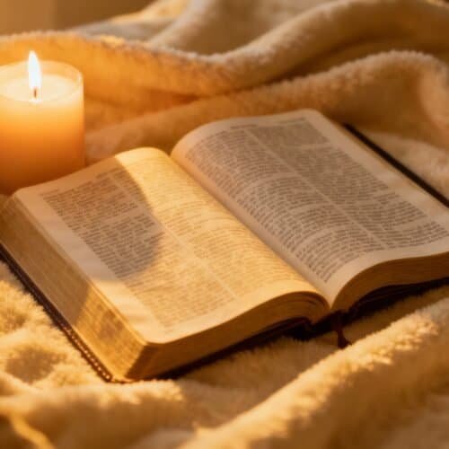Open Bible and lit candle on cozy blanket, symbolizing faith, prayer, and worship in Christian devotion. Perfect for religious or spiritual background images related to Bible songs and scripture reading.