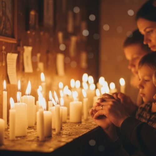 People praying with lit candles in a church, remembering loved ones, and seeking spiritual comfort.