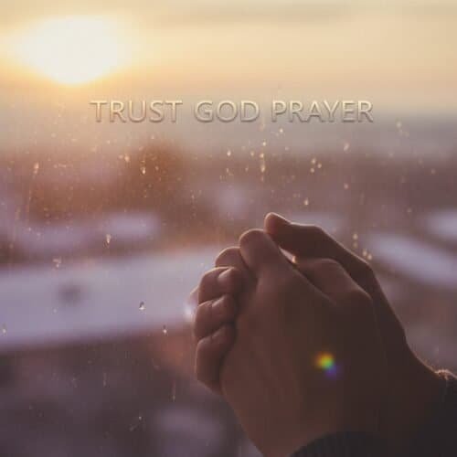 Praying hands by window with sunset view, emphasizing trust in God through prayer and faith.