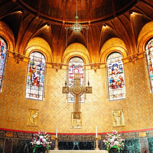 Beautiful church interior featuring vibrant stained glass windows and a central crucifix, creating a serene and spiritual atmosphere. Perfect for religious worship, prayer, and reflection.