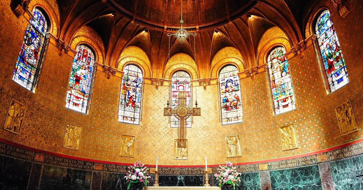 Beautiful church interior featuring vibrant stained glass windows and a central crucifix, creating a serene and spiritual atmosphere. Perfect for religious worship, prayer, and reflection.